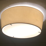 Plafonet 60 Ribbon LED ceiling light, a wide flush drum fixture with a beige fabric shade and glowing white diffuser base, mounted on a plain ceiling.