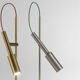 Tubino Aluminium LED Table Lamp in brushed titanium finish, angled cylindrical head on a slim stem with green loop cable, shown beside a brass version on a light background.