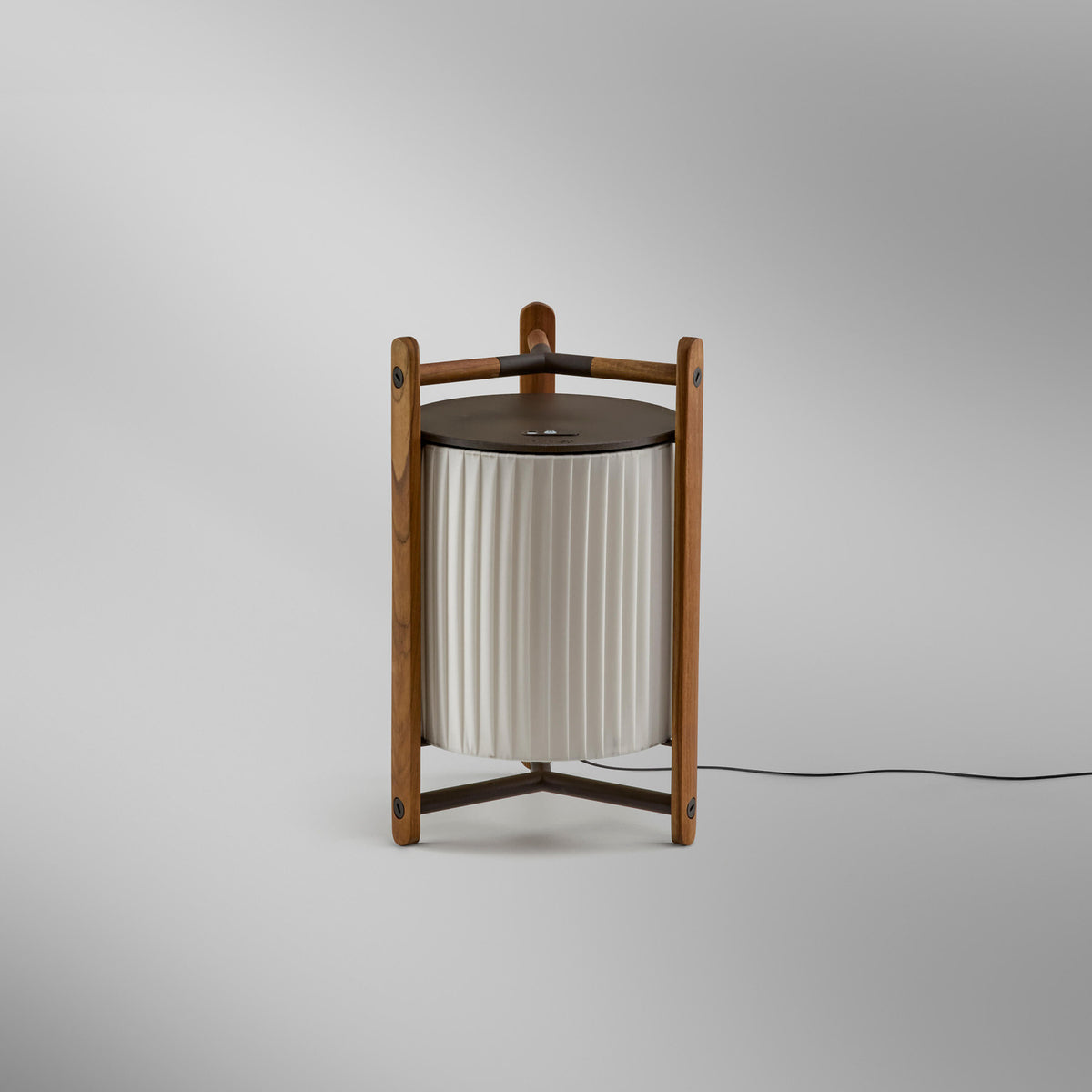 Kando M/40 Ribbon LED table lamp with pleated white translucent shade in an open wooden three-legged frame, dark top disc, on a plain light grey background.