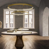 Arena Aluminium Ring LED Pendant Light in brass finish, two tiered circular hoops with integrated LED and small spotlight heads, shown above a dining table in a neutral-toned room.
