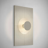 Arid Wall Light Tile in Textured Pebble Grey, a vertically fluted aluminium panel with a smooth curved centre framing a lit circular cutout, shown on a plain light background.