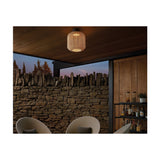 Nans PF/31 woven LED outdoor ceiling light in beige, barrel-shaped lattice shade mounted on a covered patio ceiling above a stone wall and seating area.