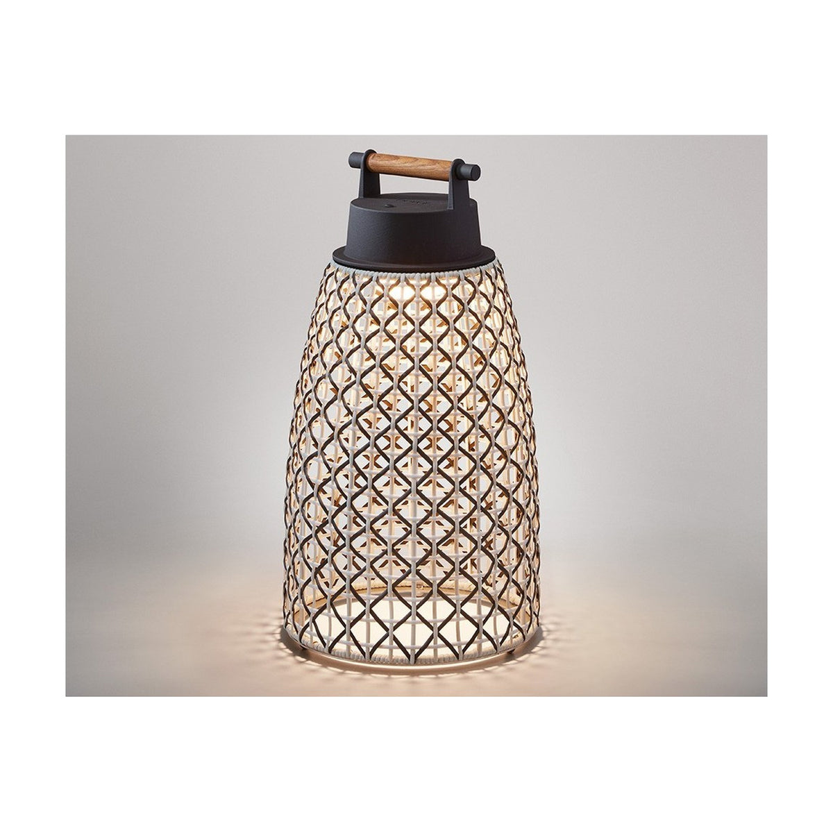 Nans Portable M/41/R rechargeable outdoor table lamp, lantern-shaped with tapered brown diamond-weave shade, dark cap, and wooden carry handle, glowing warm white on a plain light background.