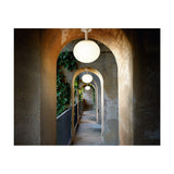 Elipse PF/30 Globe LED Outdoor Ceiling Light in white, illuminated in a vaulted stone archway corridor, shown with multiple fixtures receding along the covered walkway.