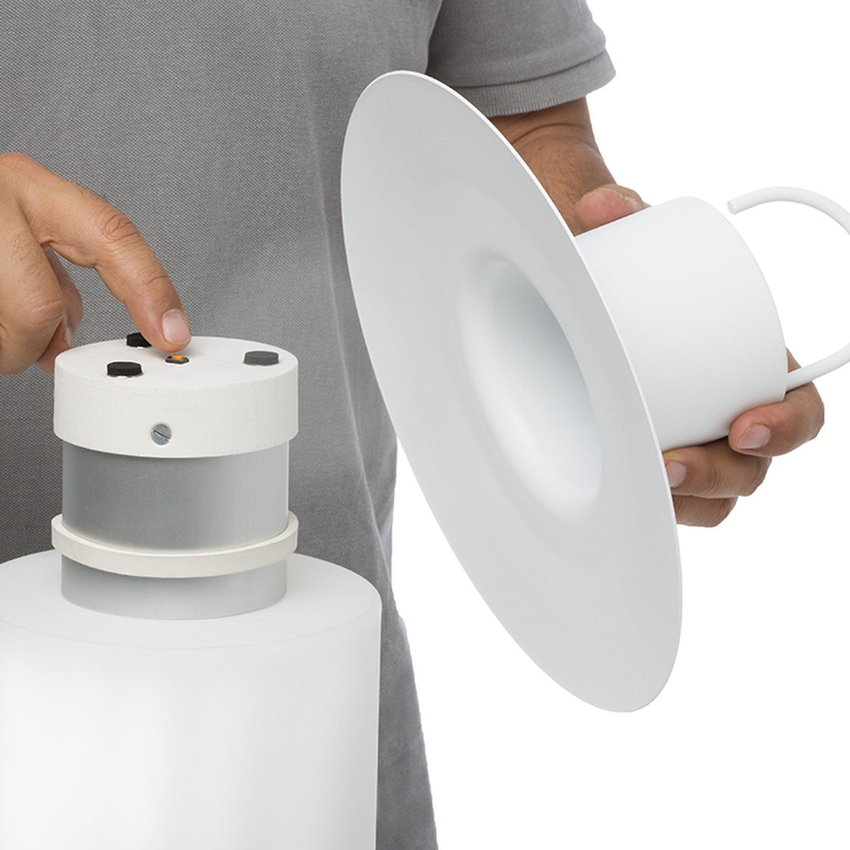Nautic LED Rechargeable Outdoor Table Lamp in white being assembled, showing the detachable cap with control buttons, wide flat brim and cylindrical diffuser base, held against a plain background.