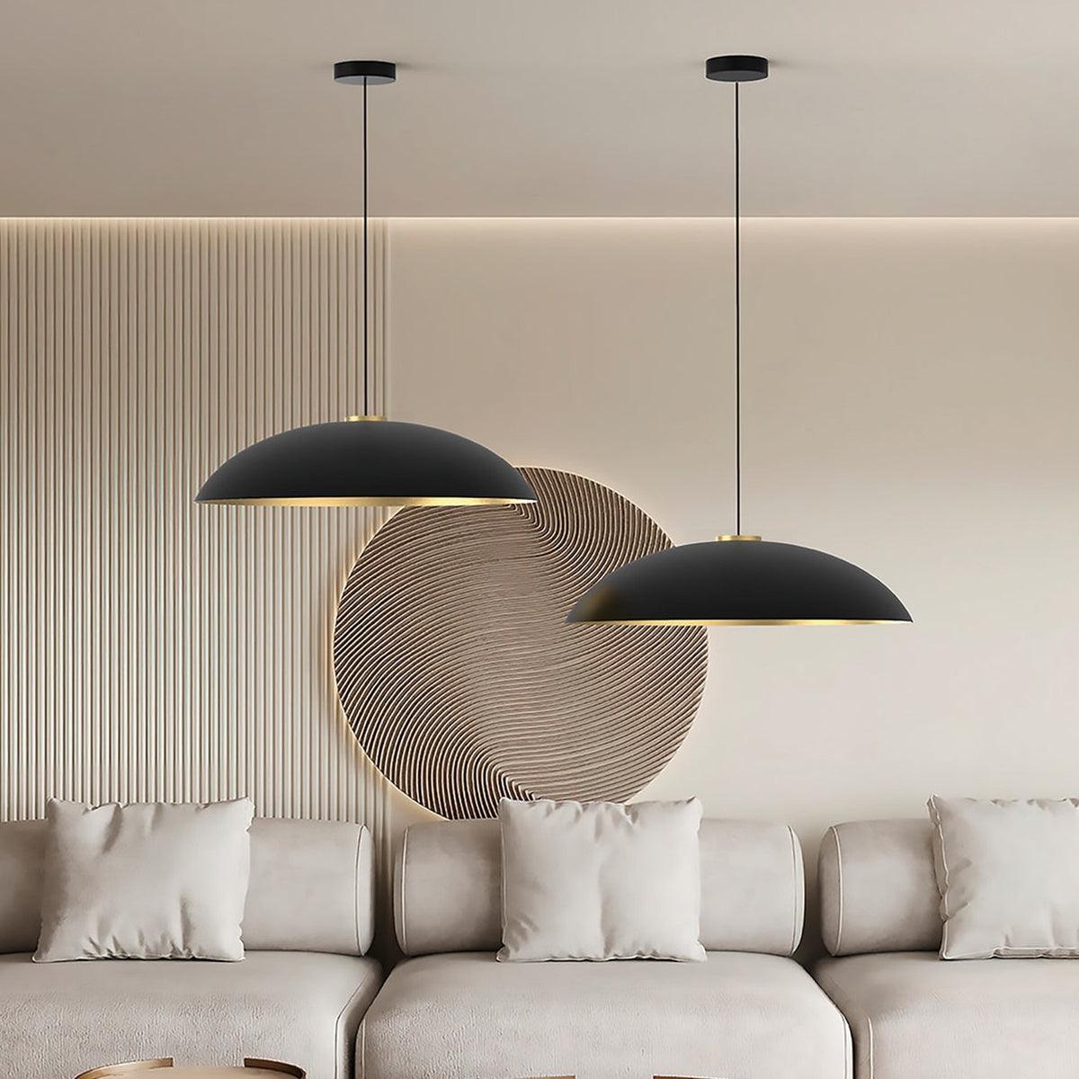 Two Rebeca dome pendant lights in matt black with gold interior, hung at different drop heights above a beige sofa in a living room setting.