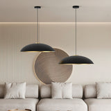 Two Rebeca dome pendant lights in matt black with gold interior, hung at different drop heights above a beige sofa in a living room setting.
