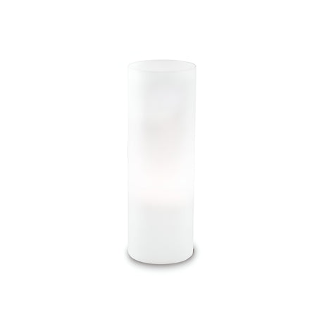 A tall, cylindrical white lamp with a minimalistic design stands on a plain, neutral background. Featuring a white glass diffuser, this Lumira Large Table Lamp - White emits a soft, diffused light that subtly illuminates its surroundings, offering a refined lighting solution.