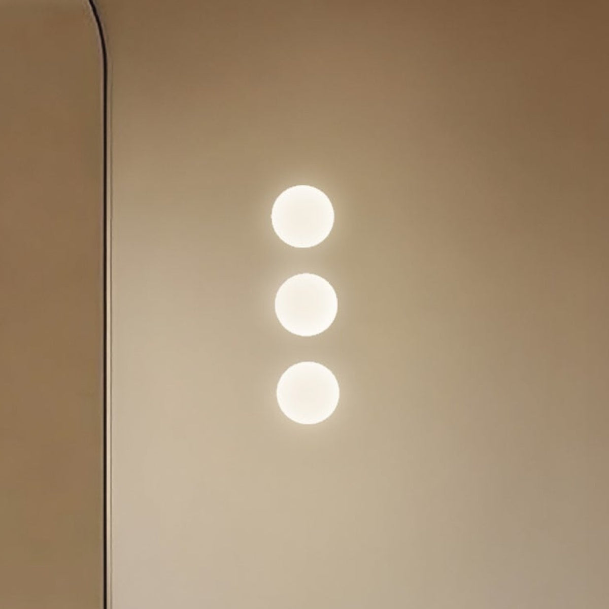 Rina Opal Glass Recessed Wall Light in polished brass, shown as three softly glowing round globes mounted vertically on a plain wall.