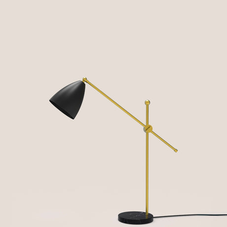 Nala Dome Adjustable Table Lamp with matt black dome shade on a long gold counterbalanced arm, pivoting on a slim gold upright with round marble base, shown against a plain light background.