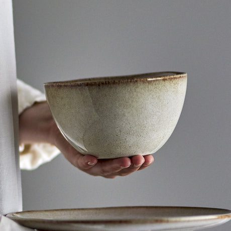 Sandrine Speckled Stoneware Bowl 15cm in grey, deep rounded sides and dark-rimmed glaze, held in hand against a plain grey background with a matching plate below.