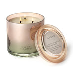 Coconut Milk Mango Glass Scented Candle with three lit cotton wicks in a high-shine pink-toned glass vessel, shown beside its glass lid on a white background.