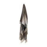 Isnel Black Striped Cotton Throw in multicoloured brown, beige, green and black stripes with knotted fringe, hanging against a plain white background.