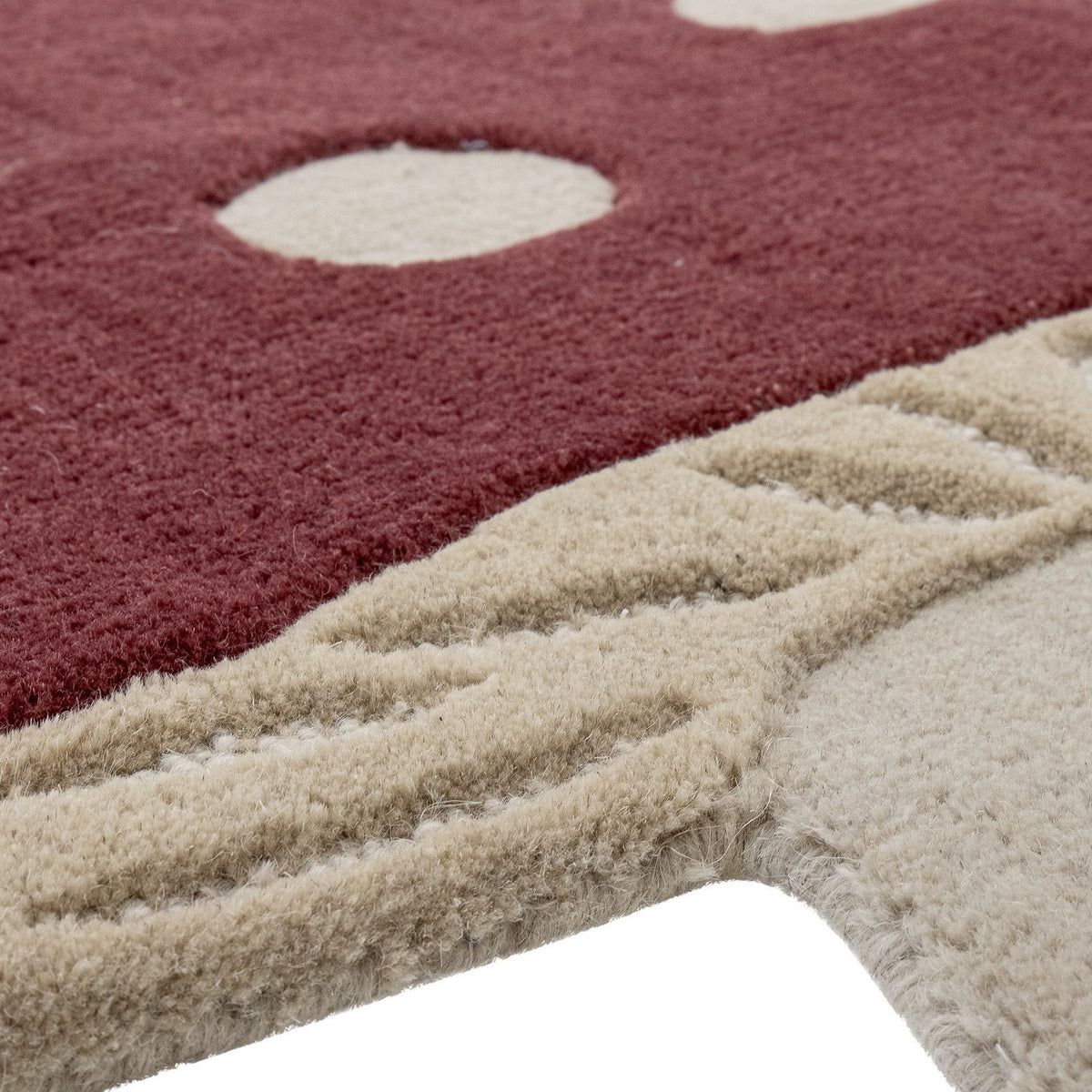 Close-up of the Mushroom Wool Rug 90x85cm in red, showing tufted red pile with cream spots meeting a textured cream stalk section with ridged detailing.