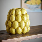 Limone Stoneware Vase 22cm in yellow, glossy ceramic moulded as tightly packed lemons with a small round opening, shown on a wooden shelf.