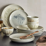 Cream Bea Crackle Stoneware 12-piece dinner set with bowls, salad and dinner plates in crackle finish with botanical grass and floral motifs, styled with a wooden spoon.
