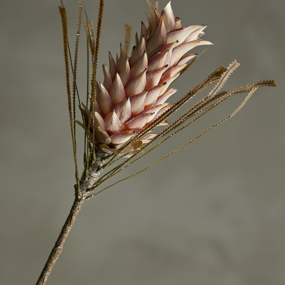 Palmflower Artificial Stem in pink, showing a cone-shaped flowerhead with layered petals and fringed leaf fronds on a textured branch-like stem, set against a plain grey background.