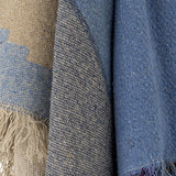 Maji Cotton Throw in Multi, close-up of woven cotton fabric showing tan, denim blue and navy colour-block panels with a tweedy flecked texture and raw fringe edge.