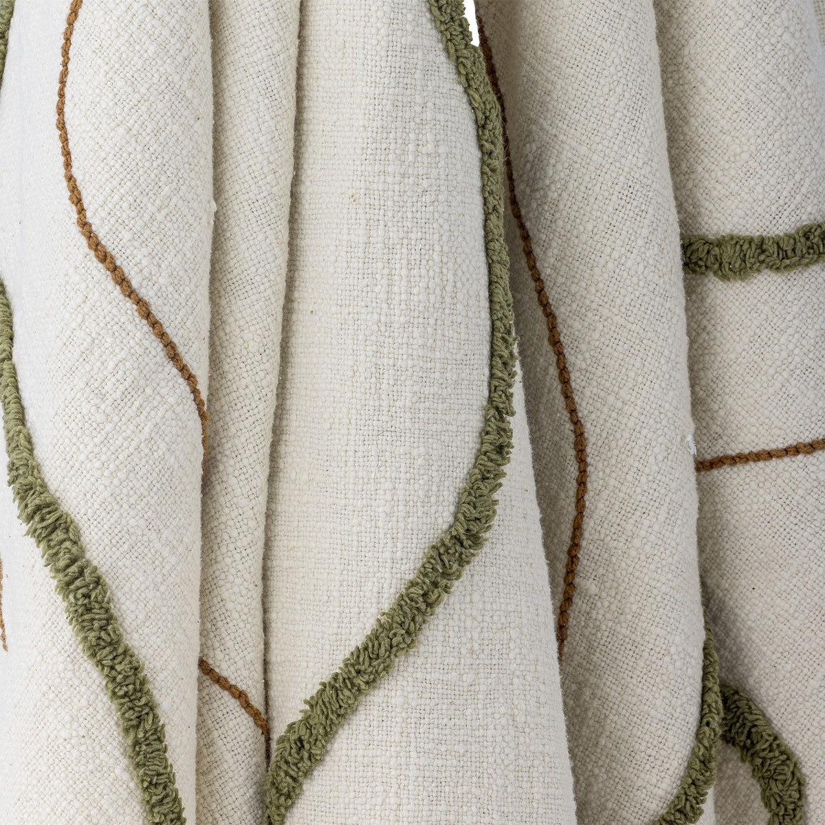 Osasio Cotton Throw in cream, close-up of the slubby woven cotton with tufted sage-green loop stitching and fine tan embroidered lines in sweeping curves.