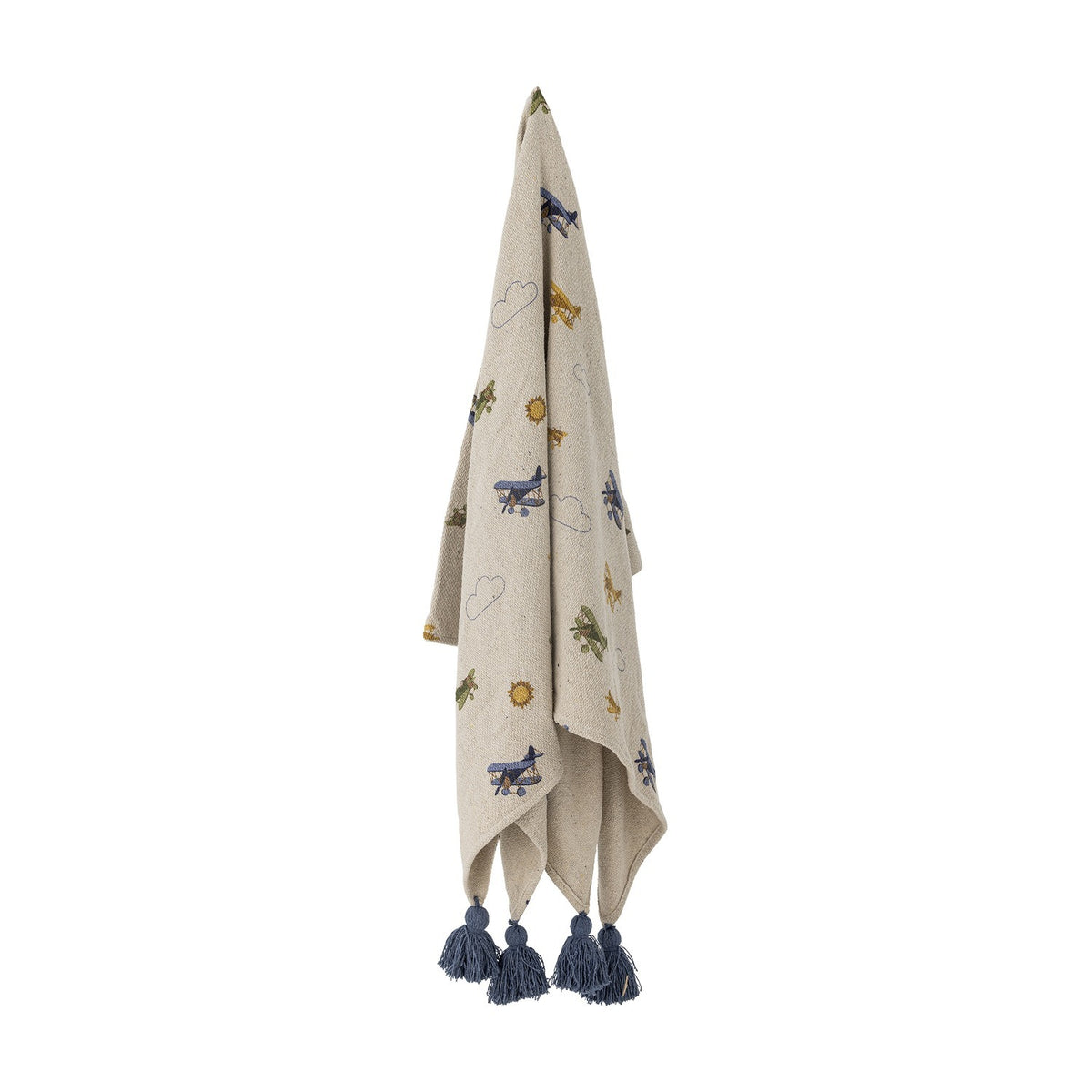Beige cotton throw for kids, patterned with embroidered biplanes, outlined clouds and suns, finished with chunky navy tassels at each corner, hanging against a plain white background.