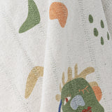 Sylvie Cotton Throw close-up in multicoloured fabric, showing abstract shapes including a sleepy-faced figure, dots, squiggles and curves in green, orange, blue and mustard tones.