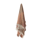 Arni Throw in Multi, a woven fabric throw in rust, terracotta and beige tones with a speckled weave and thick mixed-yarn fringe, shown hanging against a plain white background.