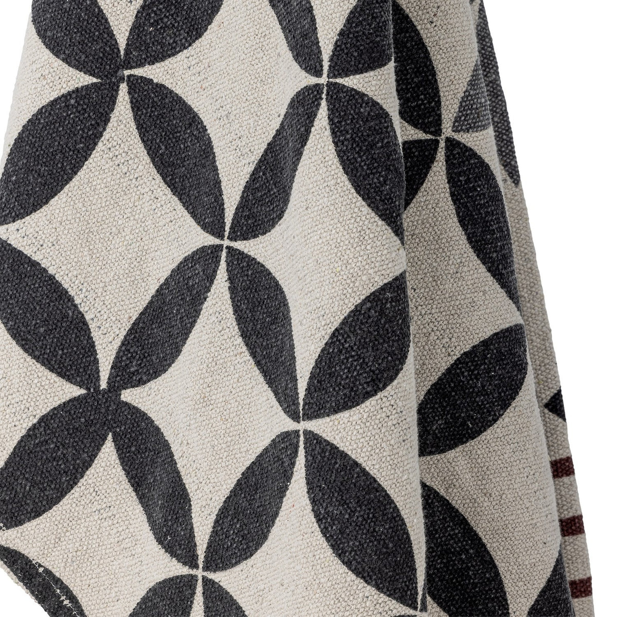 Close-up of the Forma Striped Throw in beige, showing a woven interlocking oval pattern in charcoal with a striped maroon band along one edge.