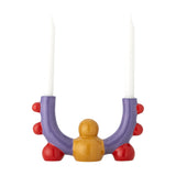 Edivia stoneware candle holder in purple with red bobble details and a yellow rounded base, two curved arms holding white taper candles, on a white background.