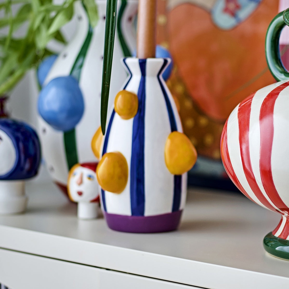 Conneli Ceramic Candle Holder in multicoloured striped dolomite ceramic with raised bumps and a purple foot band, shown among other patterned ceramic vases.