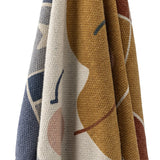 Sun Cotton Throw in multicoloured woven cotton blend, draped to show mustard, navy, cream and rust tones with sun and star motifs, set against a white background.