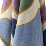 Salacia Throw in Multi, close-up of woven fabric with curved purple, green, blue, and navy bands edged in gold on a cream ground.