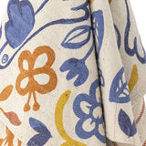 Figuria Cotton Throw in multicoloured cotton fabric, draped to show blue, rust and yellow flower, leaf and bird motifs on a cream ground.