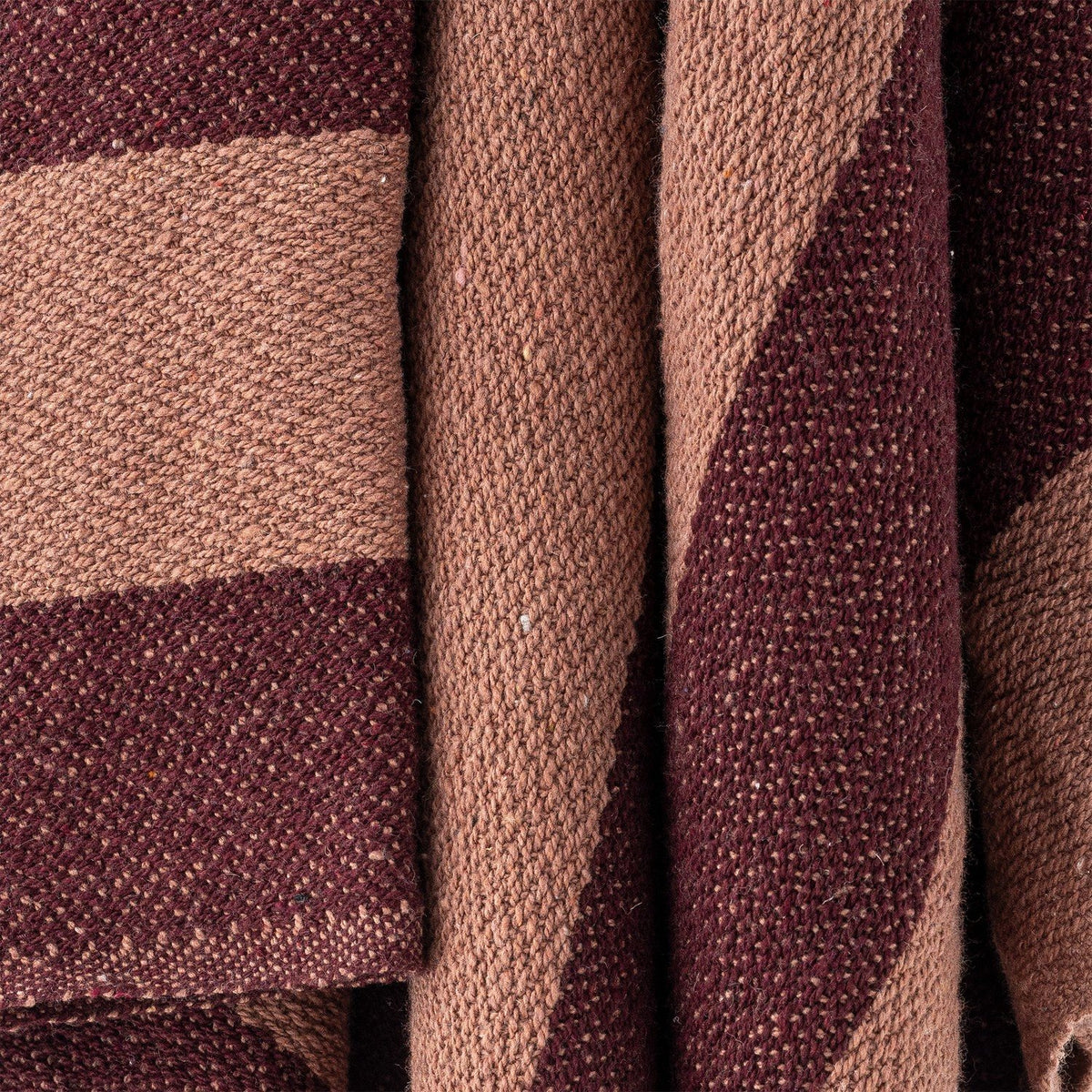 Close-up of the Frello Striped Cotton Throw in red, showing the woven texture and wide stripes in lighter and deeper red tones.
