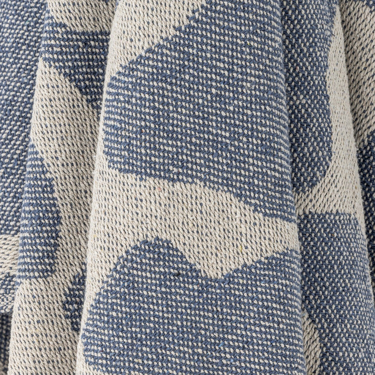 Close-up of the Salobre Cotton Throw in blue, showing a woven abstract pattern in contrasting cream tones with a textured fabric finish.
