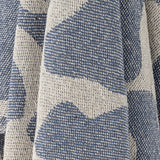 Close-up of the Salobre Cotton Throw in blue, showing a woven abstract pattern in contrasting cream tones with a textured fabric finish.