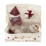 Lara Cotton Rag Doll in an open cream heart-print fabric suitcase, wearing a knitted brown bonnet and striped shorts, with a wrapped gift, fluffy ears and bow visible, on a white background.
