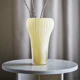 Averie Glass Vase 28cm in yellow, mouth-blown with fine vertical ribs and a curved silhouette, shown on a marble side table with dried branches.