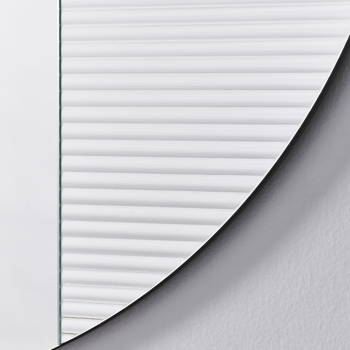 Close-up of the fluted section meeting the plain mirror, the ribs stopping along a curve that follows the outer edge.