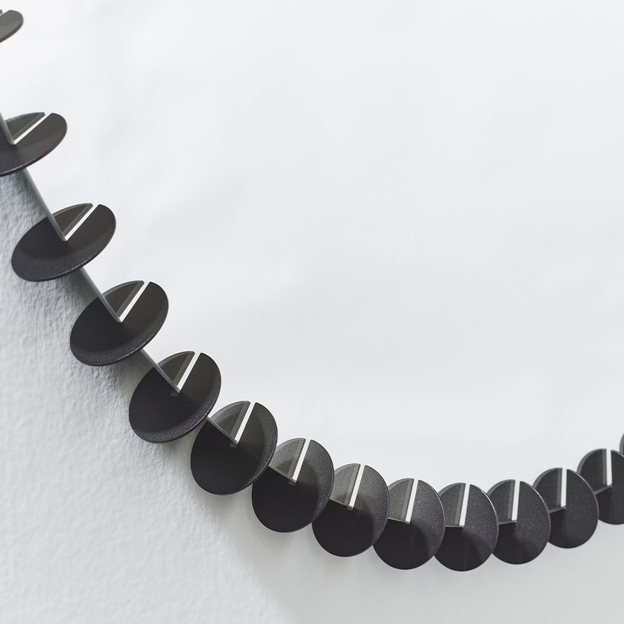 Close-up of the small black discs running around the rim, each one standing proud of the glass against a pale wall.