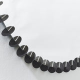 Close-up of the small black discs running around the rim, each one standing proud of the glass against a pale wall.