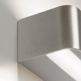 Close-up of the Toy R LED Wall Light in brushed silver, showing its slim rectangular profile with a rounded edge and integrated LED strip casting upward and downward light.
