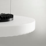 Close-up of the Côte pendant light's frosted white glass disc with ribbed underside, revealing the black integrated LED fixture above, set against a plain light background.