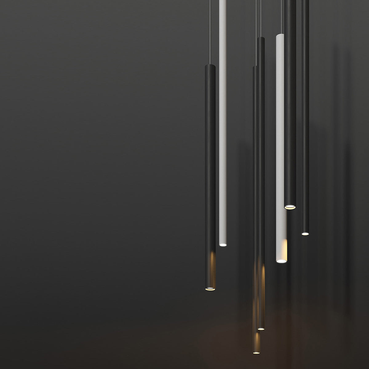 To-Be Aluminium Tube LED Pendant Light in matt black, slim cylindrical design with warm white glow at the base, shown among multiple suspended pendants against a dark background.
