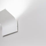 App 2 Light Aluminium LED Wall Light in white, shown in close-up with its curved panel casting a soft upward glow against a plain light grey wall.