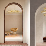 Murané R 25 ring chandelier with caramel glass spheres on a brushed champagne band, shown above a chair and table in an arched doorway.