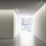 Bronx 300 recessed LED profile in black, shown as slim ceiling light lines in a minimalist hallway with white walls and a garden view.
