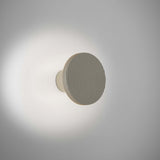 Arid A/01 round aluminium LED wall light with fine vertical fluting in Textured Pebble Grey, mounted on a short stem casting soft glow on a plain wall.
