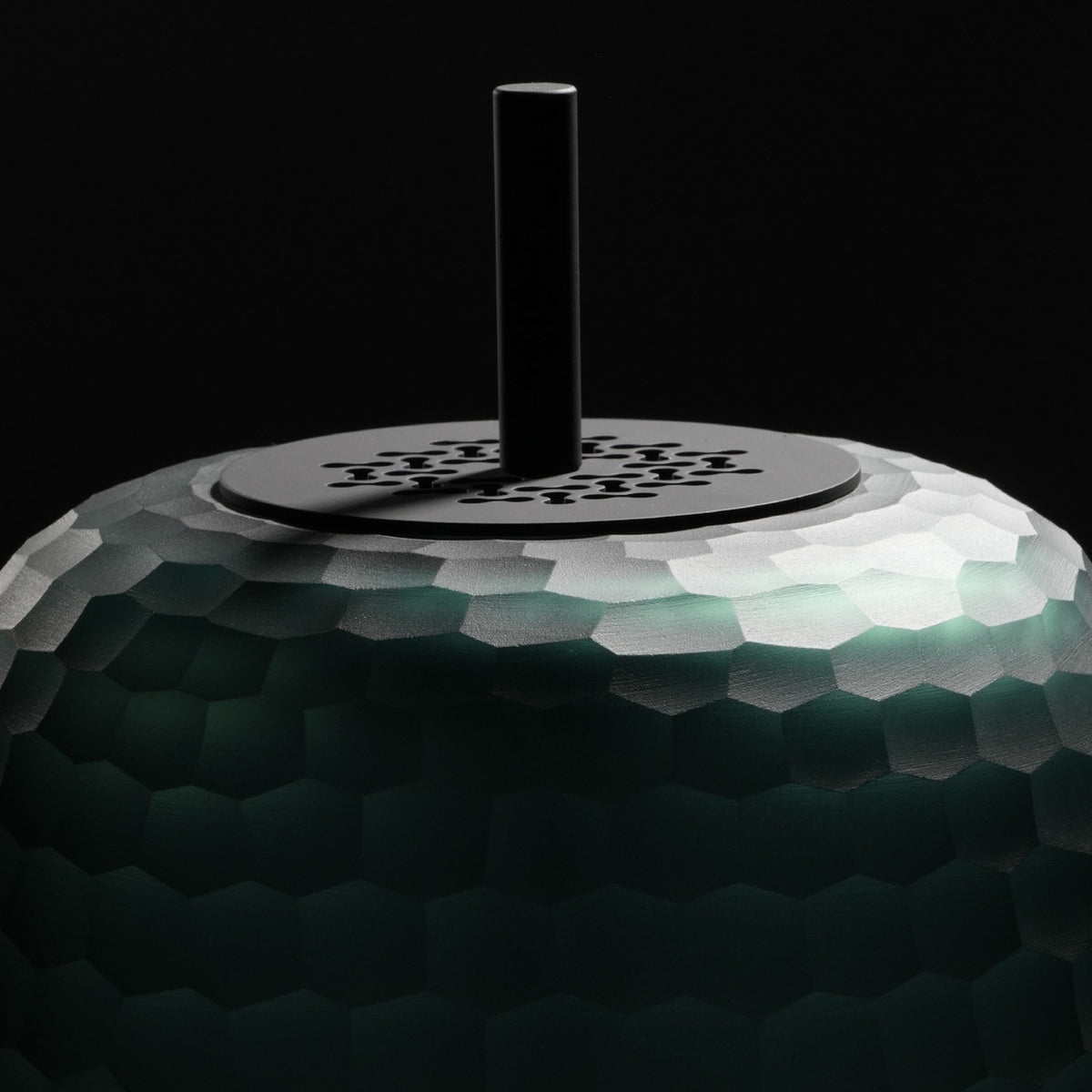 Close-up of the Adamas 23 Forest Green Glass LED Table Lamp, showing the faceted honeycomb-cut glass shade and slim black rod above a matt black base plate.
