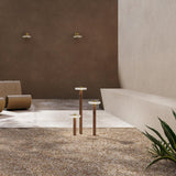 Venexia Glass LED Outdoor Floor Lamp in Wood & Matt Brass, round glass heads on slim wood columns of varying heights, set on gravel in an outdoor courtyard.
