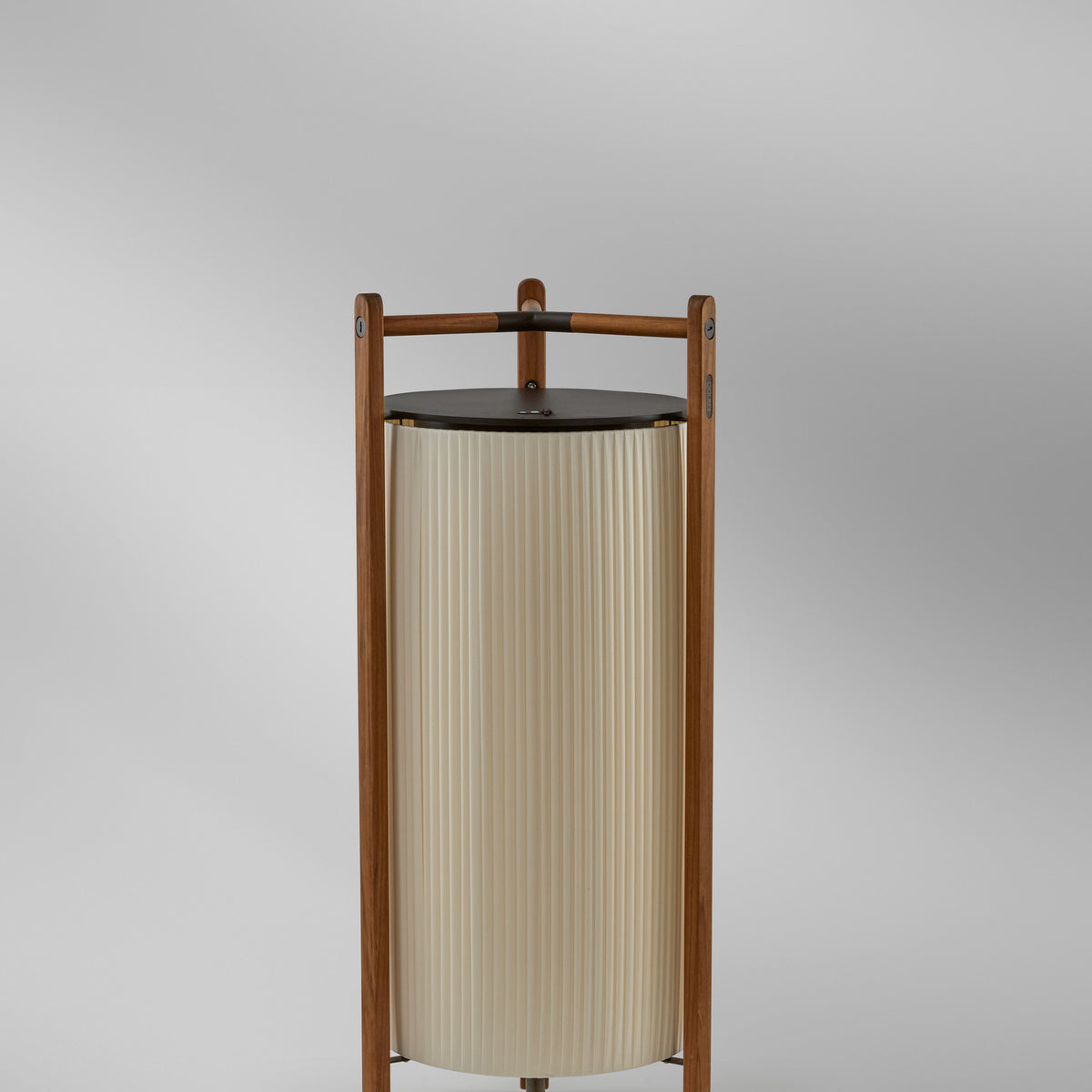 Kando P/111/R rechargeable LED floor lamp with pleated white ribbon shade, dark top disc, and slim wooden frame, shown close-up on a plain grey background.